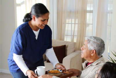 nurse serving a meal to senior couple