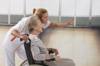 nurse pointing at the right and smiling senior woman with wheelchair 