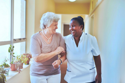 nurse and senior woman having a conversation while walking at the hallway