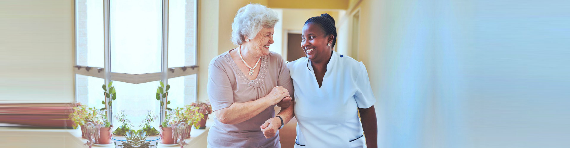 nurse and senior woman having a conversation while walking at the hallway